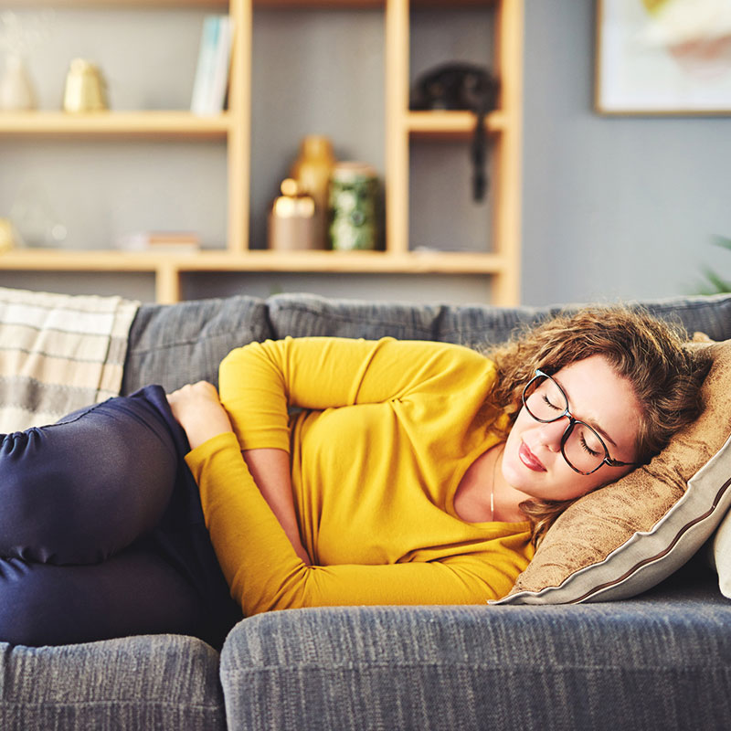 Woman lying on couch holding stomach