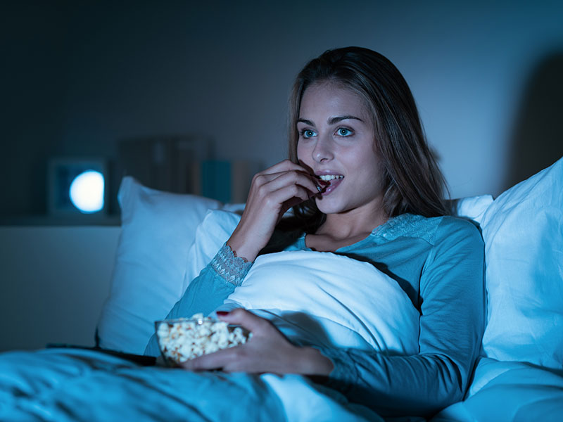 Woman eating popcorn in bed