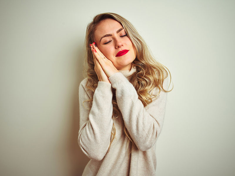 Woman posing with hands together while smiling with closed eyes