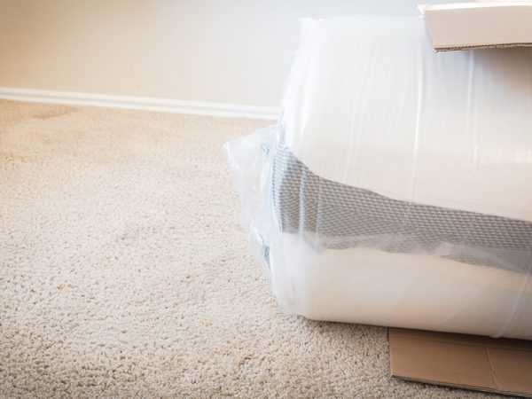 Foam and latex hybrid material mattress being unboxed from cardboard box