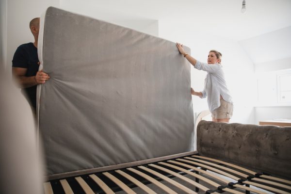 Mature couple are setting up their bed in their new home